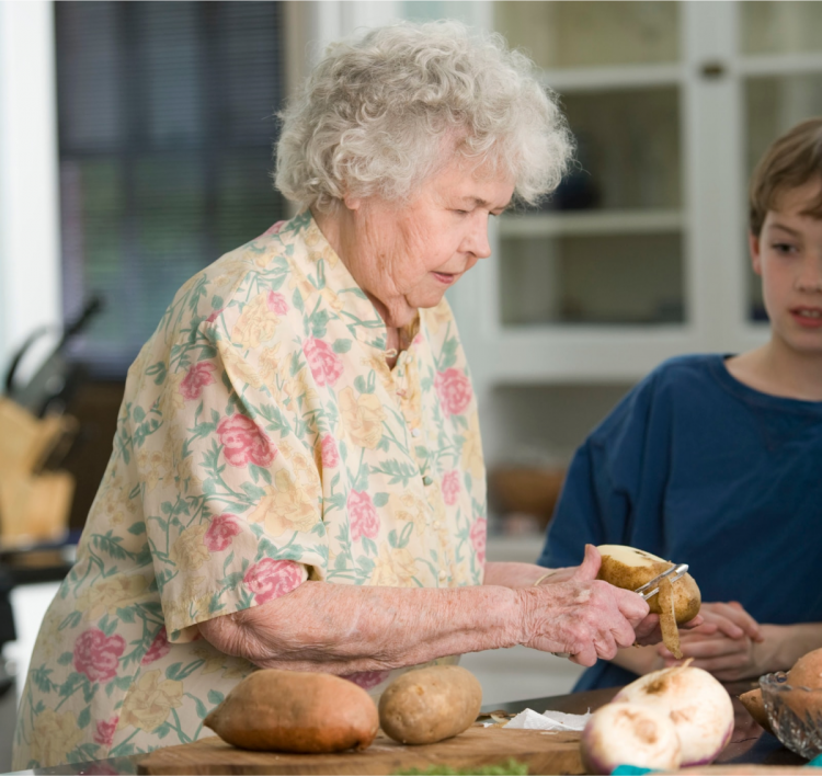 vanha nainen kuorii perunoita ja lapsi katselee vieressä